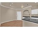 Bright interior showcasing the kitchen area with wooden floors, archway shelving, black countertops, and white cabinets at 860 N Orange Ave # 306, Orlando, FL 32801