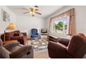 Cozy living room with hardwood floors, a ceiling fan, and a large window offering natural light at 1125 Emerald Dr, Mount Dora, FL 32757