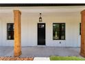 Front door view with black craftsman-style door, windows, stained wood columns, and a hanging light fixture at 12193 Sw 69 Pl, Ocala, FL 34481