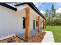 Charming front porch showing stained wood columns, house number, board and batten siding, and professional landscaping at 12193 Sw 69 Pl, Ocala, FL 34481