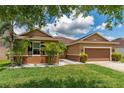 Charming single-story home with a well-manicured lawn, complemented by white rock landscaping and palm trees at 12845 Sawgrass Pine Cir, Orlando, FL 32824