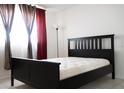 Bedroom features a dark wood bed frame, neutral tile, and curtains on a window at 1504 Virginia Ave # 105, Daytona Beach, FL 32114