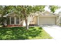 Charming home featuring a well-manicured lawn, mature trees, and attached two-car garage at 2343 Walnut Heights Rd, Apopka, FL 32703