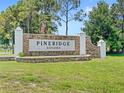 Stone sign marking entrance to Pineridge Estates with lush green grass at 2409 Pinyon Ct, Kissimmee, FL 34746