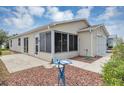 Rear exterior of a beige single-story home with a screened lanai and stone landscaping at 2714 Moncayo Ave, The Villages, FL 32162