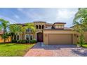 Elegant two-story home featuring a lush lawn, landscaping, paver driveway, and porte-cochere at 3041 Boating Blvd, Kissimmee, FL 34746