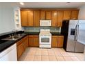 Functional kitchen with wooden cabinets, stainless steel appliances, and black countertops on tile flooring at 3549 Wilshire Way Rd # 56, Orlando, FL 32829