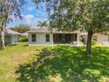 Spacious backyard with an enclosed patio, lush lawn, and mature shade trees at 5560 Squires Dr, Leesburg, FL 34748