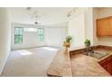 Bright living area features large windows and a ceiling fan with an open view of the kitchen at 6169 Metrowest Blvd # 308, Orlando, FL 32835
