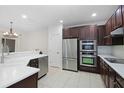 Modern kitchen with stainless steel appliances, dark cabinets, and bright white countertops at 6941 Piazza St, Orlando, FL 32819