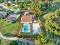 Aerial view of the property, featuring the house, pool, sand volleyball court, and verdant landscaping at 6969 Edgeworth Dr, Orlando, FL 32819