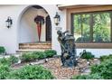 View of landscaped front entry, including a small decorative statue and colorful potted flowers at 6969 Edgeworth Dr, Orlando, FL 32819