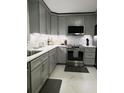 Modern kitchen with gray cabinets, stainless steel appliances, sleek countertops, and stylish backsplash, ready for culinary adventures at 983 Bucksaw Pl, Longwood, FL 32750