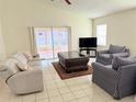 Bright and spacious living room featuring tile floors, modern furniture, and sliding glass doors at 12756 Maribou Cir, Orlando, FL 32828