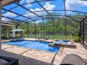 Inviting screened-in pool area with a spa, waterfall feature, and comfortable seating at 20199 Sweetwood Ln, Clermont, FL 34715