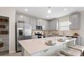 Modern kitchen featuring stainless steel appliances, gray cabinets, a large quartz island, and barstool seating at 245 Streamliner Way, Groveland, FL 34736