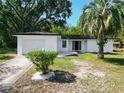 Beautiful exterior view of a white home showcasing a well-kept lawn, landscaping, and attached garage at 43 Lake Court Loop, Ocala, FL 34472