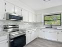 Well-lit kitchen features stainless steel appliances, white cabinets, and marble backsplash at 43 Lake Court Loop, Ocala, FL 34472