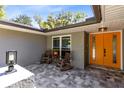 Cozy front porch with seating area, an orange entry door, and stylish paving at 5370 Whispering Pine Cir, St Cloud, FL 34771