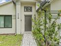 Inviting front entrance featuring a sleek, dark door, decorative plants, and manicured landscaping at 1112 Winding Water Way, Clermont, FL 34714