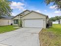 Charming single-story home displaying a clean two-car garage and well-kept lawn with a vibrant splash of nature at 1112 Winding Water Way, Clermont, FL 34714