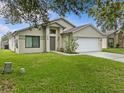 Charming single-story home boasting a manicured lawn, neutral stucco, and an attached two-car garage at 1112 Winding Water Way, Clermont, FL 34714