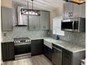 Modern kitchen featuring sleek cabinets, stainless steel appliances, granite countertops, and a stylish backsplash at 1112 Winding Water Way, Clermont, FL 34714