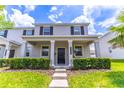 Charming two-story home featuring a covered porch, gray stucco, and lush, landscaped front yard at 15030 Book Club Rd, Winter Garden, FL 34787