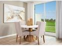 Cozy dining area with backyard view, featuring a white round table with modern upholstered chairs at 16382 Bird Of Paradise Ave, Clermont, FL 34714