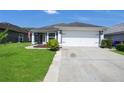 Inviting single-story home with a well-manicured lawn, attached two-car garage, and a patriotic American flag at 204 Bay Meadow Dr, Kissimmee, FL 34746