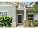 Close-up view of the front door with stone pillar accent, neutral exterior, and manicured hedges at 2125 Shackley Pl, Apopka, FL 32703