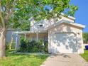 Charming two-story home featuring a covered porch, garage, and mature trees at 2320 Pebble Brook Rd, Kissimmee, FL 34741