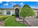 Inviting front entrance with arched doorway, manicured landscaping, and brick-paved driveway at 3677 Serena Ln, Clermont, FL 34711