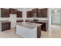 Modern kitchen with dark wood cabinets, granite countertops, and stainless steel appliances at 3975 Kennebunk Loop, Mount Dora, FL 32757