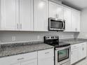 Well-appointed kitchen with white cabinets, stainless steel appliances, and granite countertops, offering style and functionality at 596 Sun Warbler Way, St Cloud, FL 34771