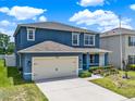 Well-maintained two-story home with blue siding, a spacious two-car garage, and lush green lawn at 5967 Churchill Square Way, Groveland, FL 34736
