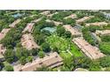 An aerial shot of the villa community boasting lush green spaces, mature trees, and a tennis court at 6205 Miramonte Dr # 103, Orlando, FL 32835