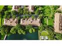 Aerial view of a lakefront community featuring lush landscaping, a pool, and well-maintained buildings at 6205 Miramonte Dr # 103, Orlando, FL 32835