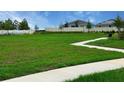 Green space with walking path, bench, and view of houses with solar panels in a fenced community at 734 Ginger Dr, Haines City, FL 33844