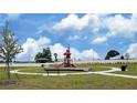 Community playground featuring play structure, benches, walking path and green space against a bright blue sky at 734 Ginger Dr, Haines City, FL 33844