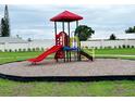 Playground structure featuring a red roof, red slide, and yellow ladder for climbing. Set in a green lawn and mulch at 734 Ginger Dr, Haines City, FL 33844