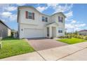 Angle view of a beautiful two-story home highlighting the brick driveway, attached two-car garage, and manicured lawn at 9027 Coral Cape St, Kissimmee, FL 34747