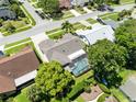 Aerial view of the home featuring a screened pool, lush landscaping, and neighborhood streets at 1172 Trotwood Blvd, Winter Springs, FL 32708