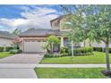 Charming two-story home with a brick driveway, manicured lawn, and vibrant landscaping at 14078 Alafaya Oak Bnd, Orlando, FL 32828
