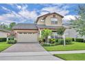Charming two-story home with a brick driveway, manicured lawn, and vibrant landscaping at 14078 Alafaya Oak Bnd, Orlando, FL 32828