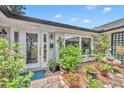 Inviting front entrance with a glass door, large window and abundant greenery in a charming garden setting at 1441 Sunnyside Dr, Maitland, FL 32751