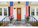 View of front porch decorated with American flags and planters with pink flowers at 2505 Amherst Ave, Orlando, FL 32804