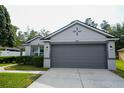 Well-maintained home features a two-car garage, gray exterior, and tidy landscaping at 3422 Heath Dr, Deltona, FL 32725