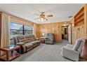 Cozy living room with wood paneling, carpeted floors, and natural light from a large window at 911 Ursula St, Ocoee, FL 34761