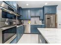 Modern kitchen with stainless steel appliances, stylish blue cabinetry and a sleek tile backsplash at 11 S University Cir, Deland, FL 32724